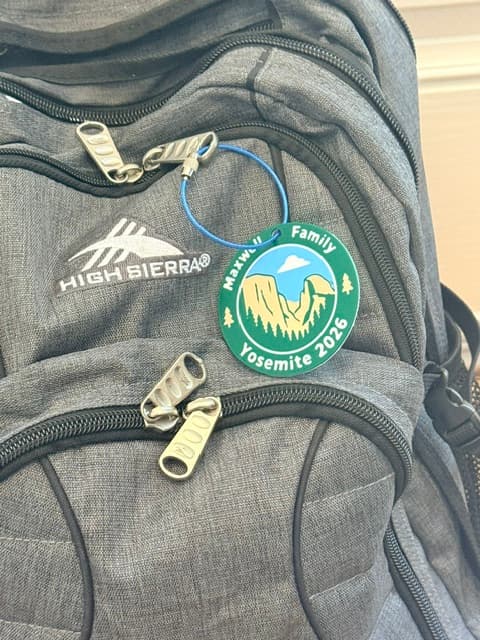 A custom family-trip backpack badge clipped to a backpack