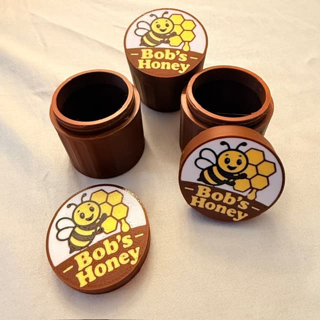 3D-printed jars with a custom bee-themed "Bob's Honey" label on the lids